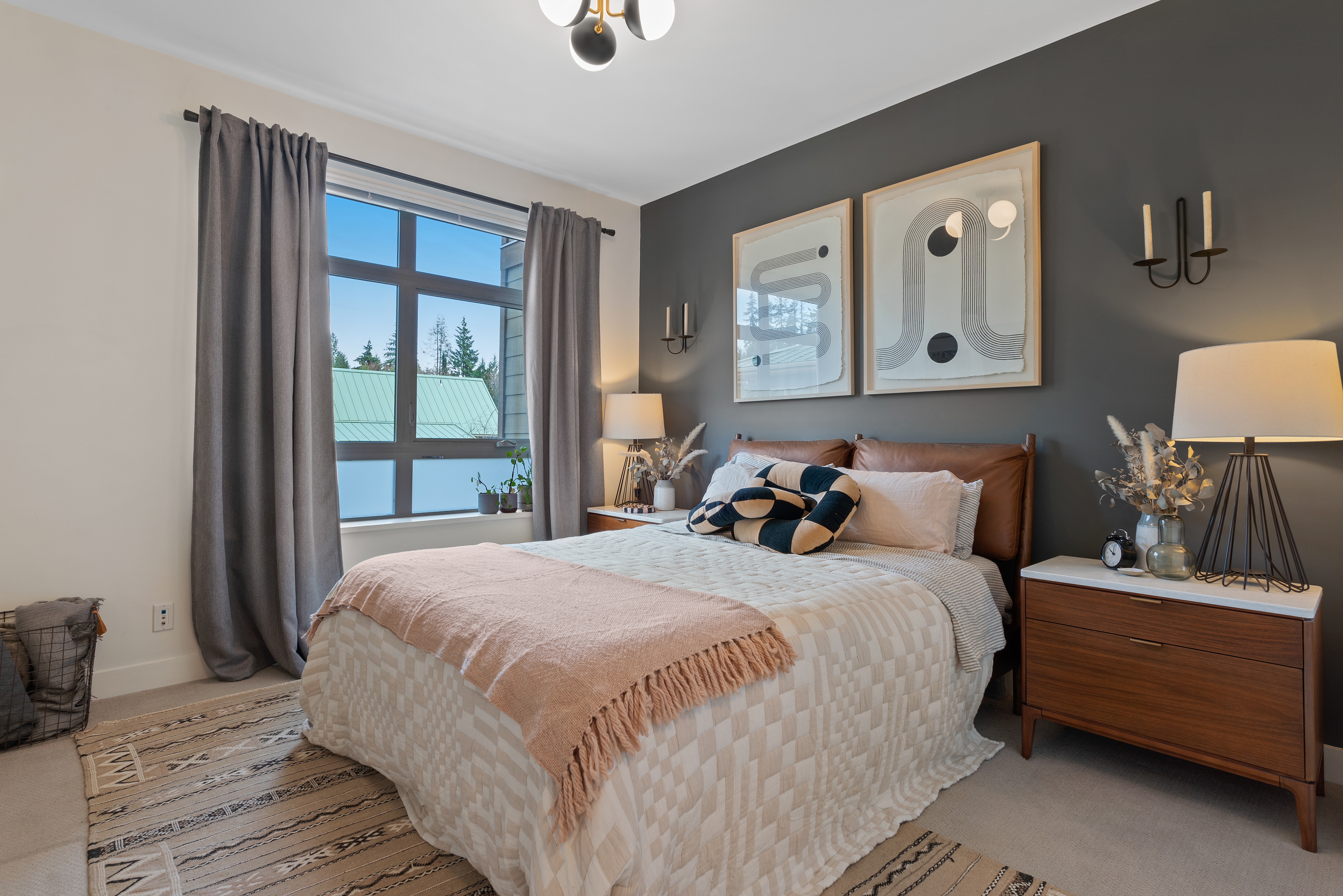 Bedroom with eclectic artwork, white bedspread, pillows, and large windows.