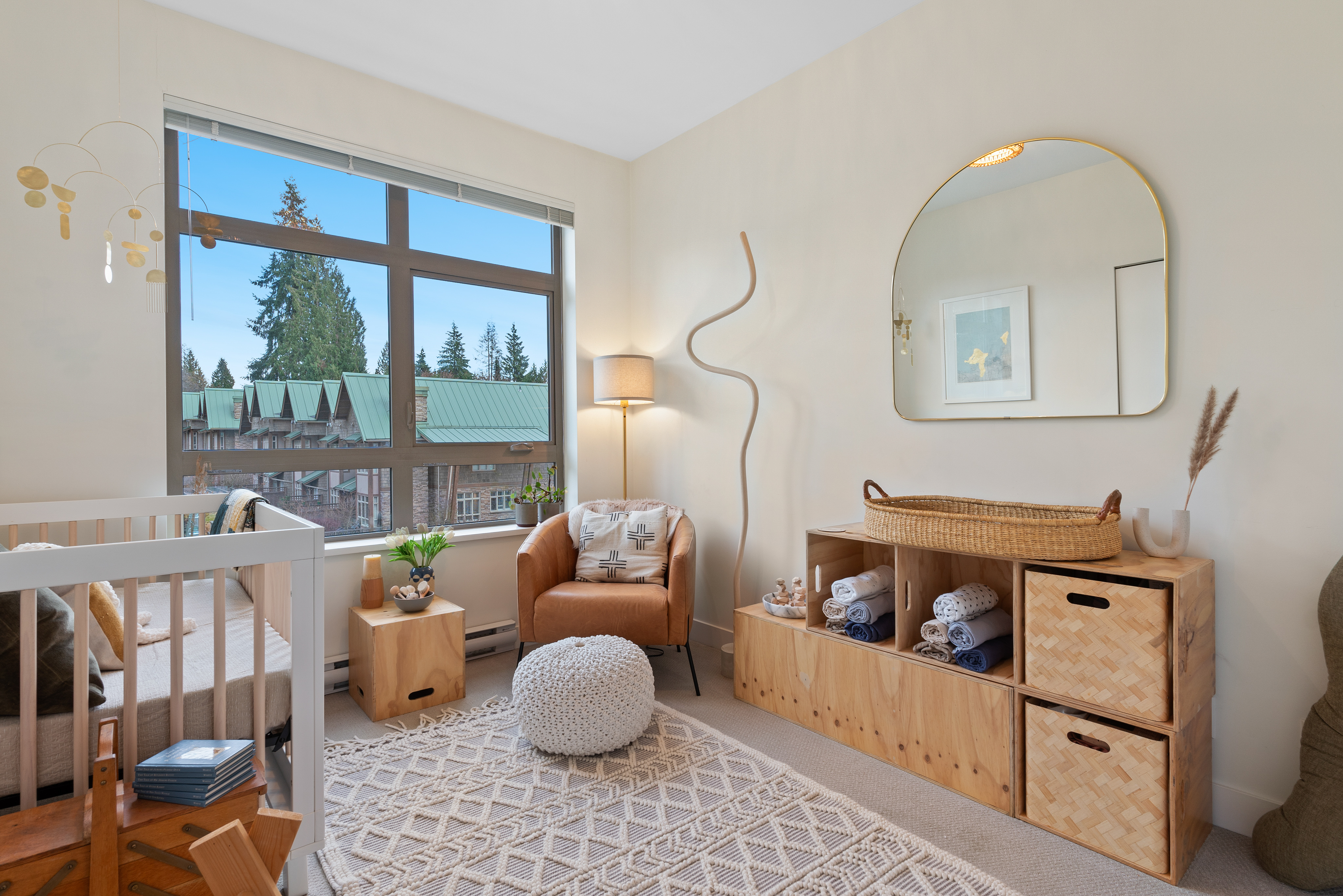Nursey with a crib, dresser, and armchair, decorated in neutral pink and brown tones.